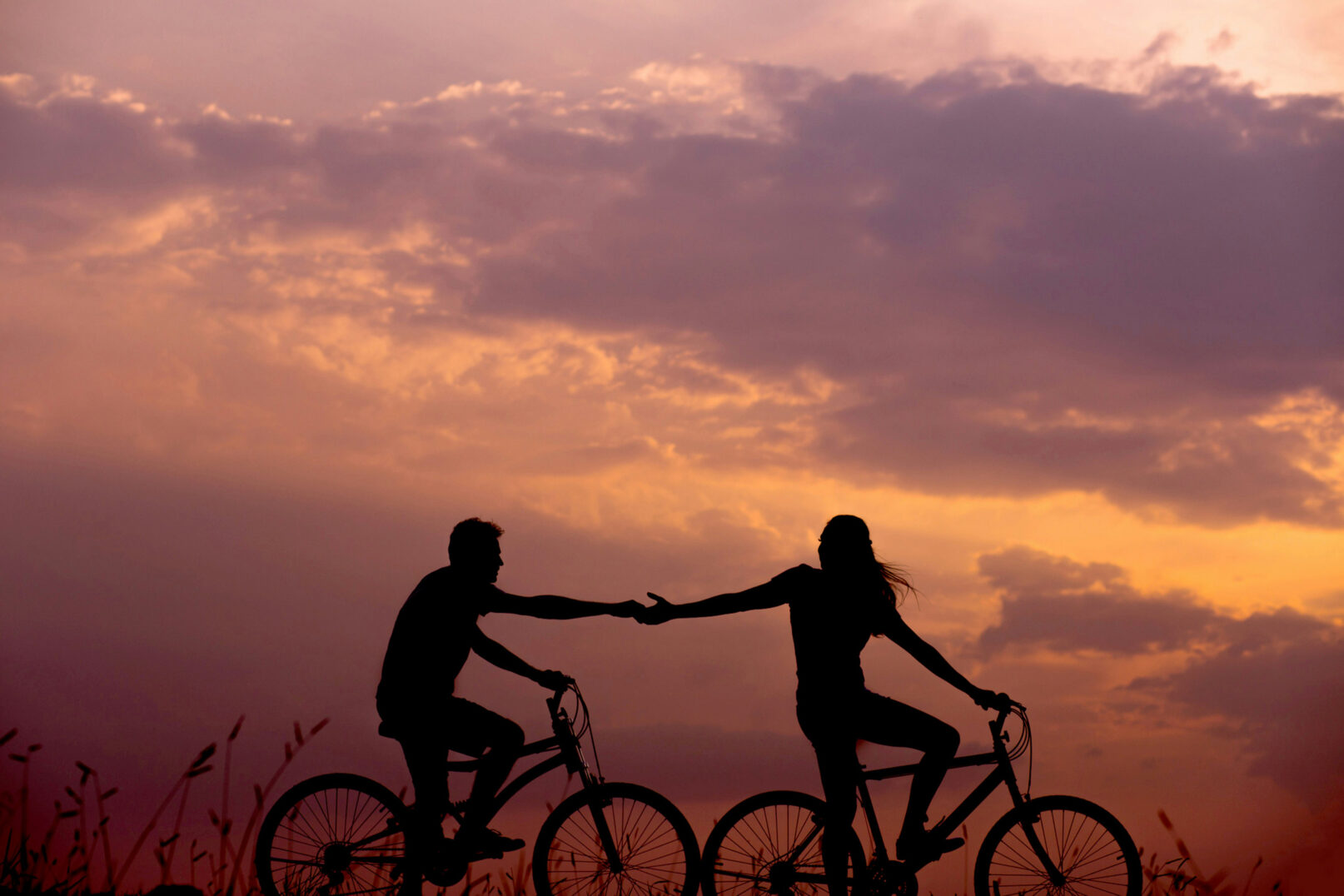 Two cyclists on the Cornish coast path at sunset
