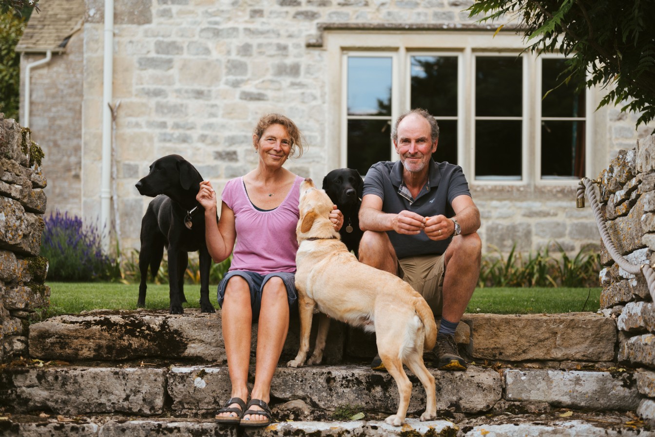 People with dogs outside a stone cottage in Cornwall